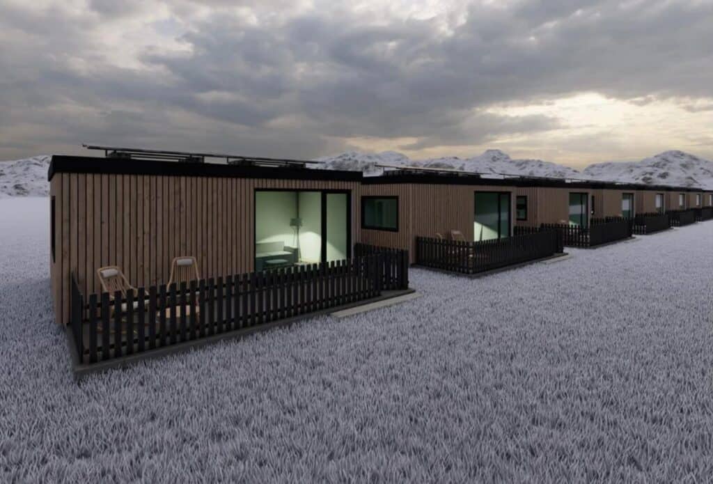 Casas de madera en paisaje nevado al atardecer.