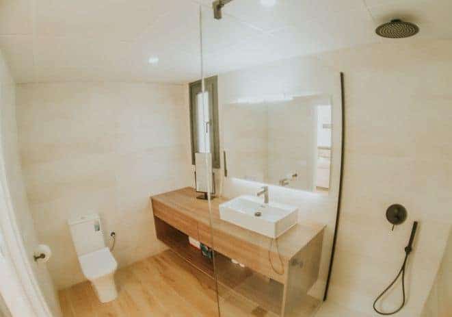Moderno baño con ducha y espejo grande.